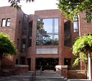 A brick building with large windows, surrounded by trees, likely representing an academic or institutional facility.